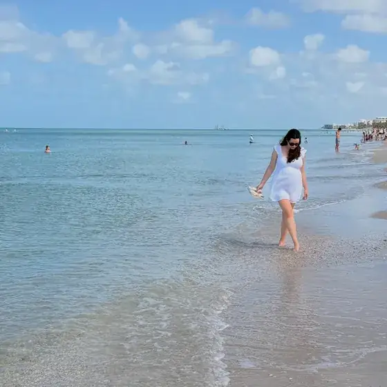Walking along the shoreline in shallow water on a bright day.